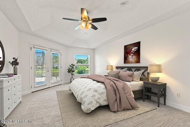 bedroom with access to exterior, a textured ceiling, light carpet, and a raised ceiling