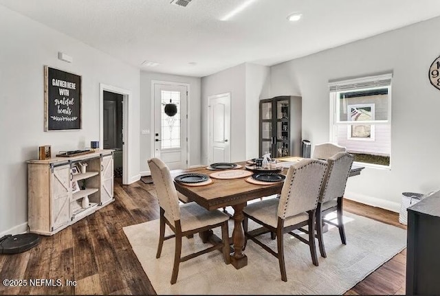 dining space featuring a wealth of natural light and dark wood-type flooring