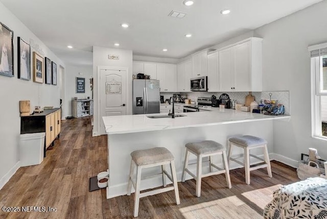 kitchen featuring a kitchen breakfast bar, kitchen peninsula, sink, and stainless steel appliances