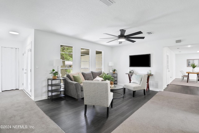 living room with a textured ceiling, dark hardwood / wood-style floors, and ceiling fan