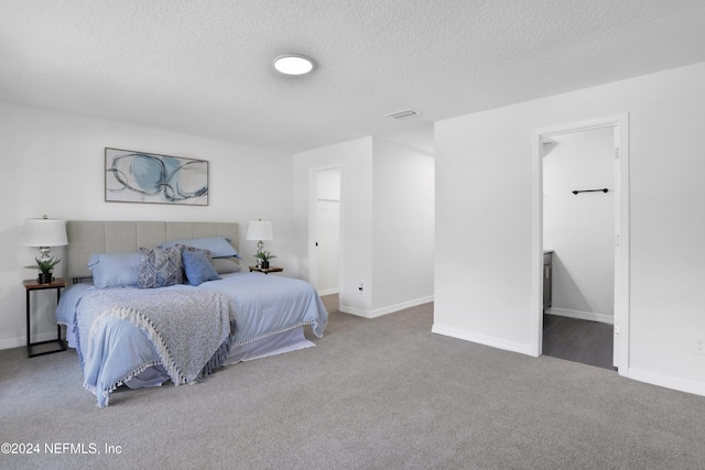 carpeted bedroom with a textured ceiling and ensuite bath