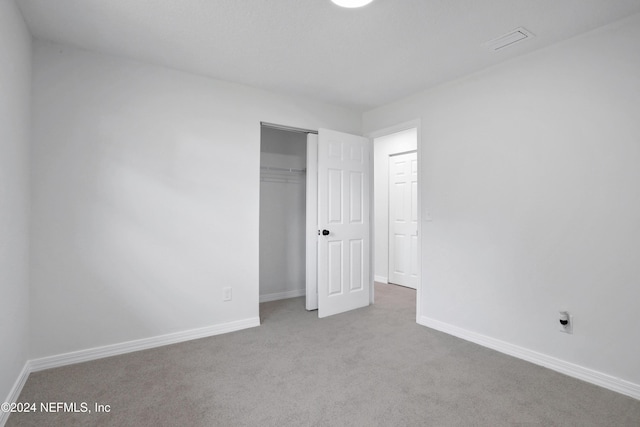 unfurnished bedroom featuring a closet and light colored carpet