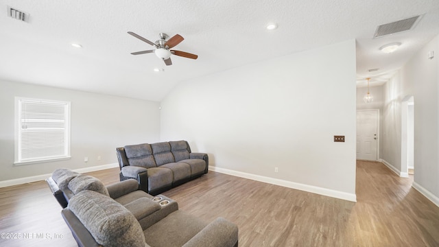 living room featuring a textured ceiling, light wood-type flooring, ceiling fan, and lofted ceiling