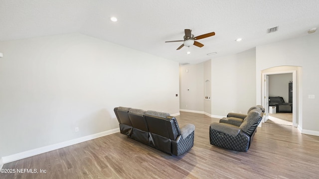 living area with hardwood / wood-style floors, ceiling fan, lofted ceiling, and a textured ceiling