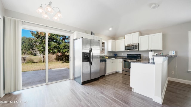 kitchen with kitchen peninsula, appliances with stainless steel finishes, decorative light fixtures, and white cabinetry