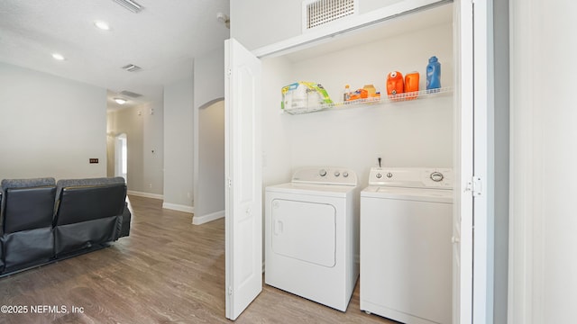 laundry room with a textured ceiling, hardwood / wood-style flooring, and washing machine and clothes dryer