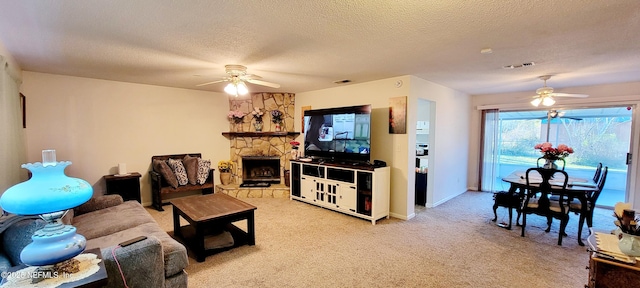 living room featuring a fireplace, ceiling fan, light colored carpet, and a textured ceiling