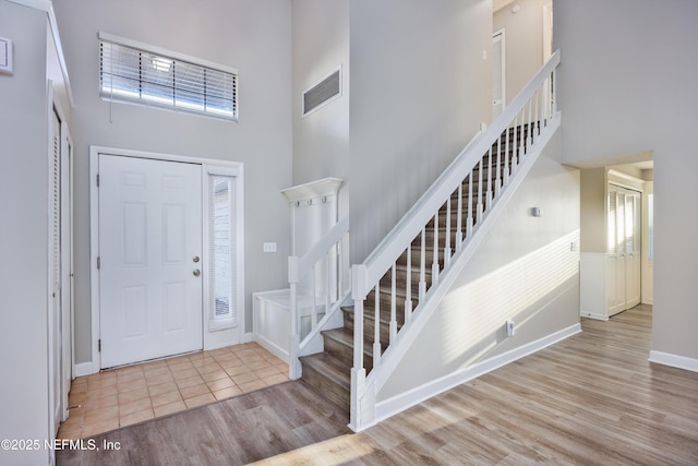 entryway featuring a towering ceiling and light hardwood / wood-style floors