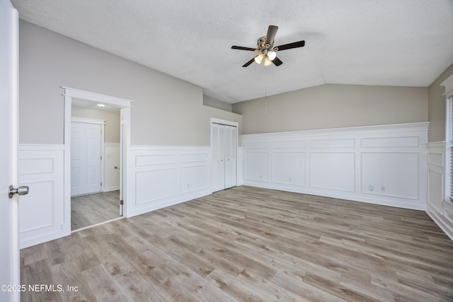 unfurnished bedroom featuring vaulted ceiling, light hardwood / wood-style flooring, and a textured ceiling