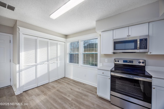 kitchen with white cabinetry, appliances with stainless steel finishes, a wealth of natural light, and light hardwood / wood-style floors