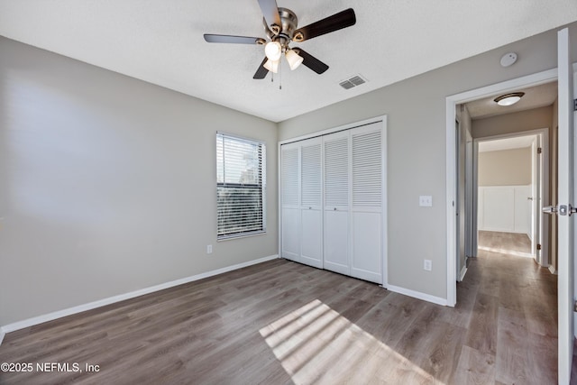 unfurnished bedroom with ceiling fan, a closet, light hardwood / wood-style flooring, and a textured ceiling