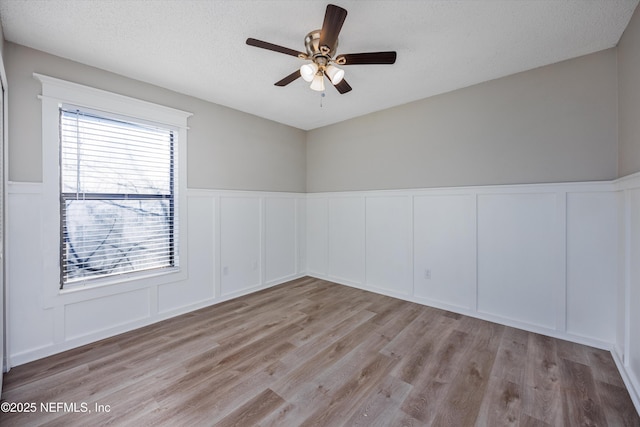 spare room with ceiling fan, a textured ceiling, and light wood-type flooring