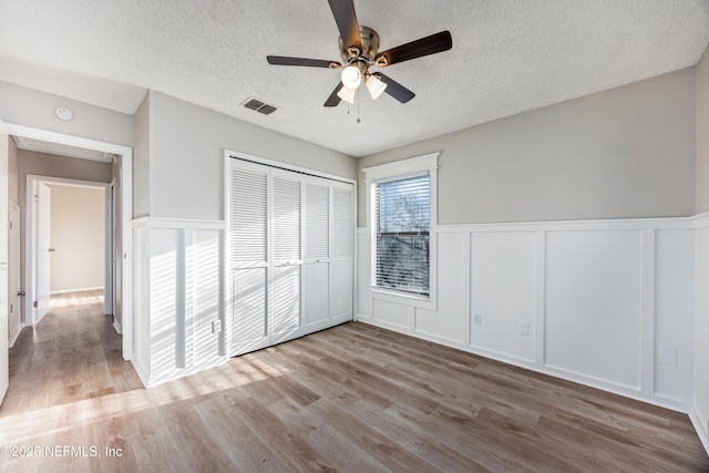 unfurnished bedroom with ceiling fan, a closet, a textured ceiling, and light hardwood / wood-style flooring