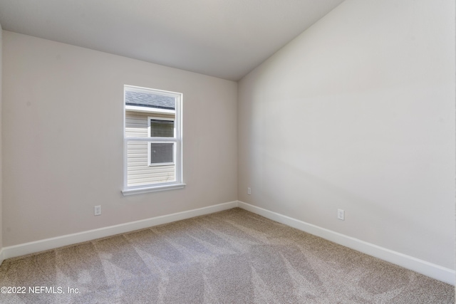 carpeted spare room with vaulted ceiling