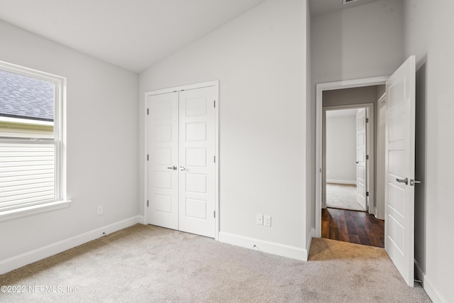 unfurnished bedroom with multiple windows, lofted ceiling, a closet, and carpet