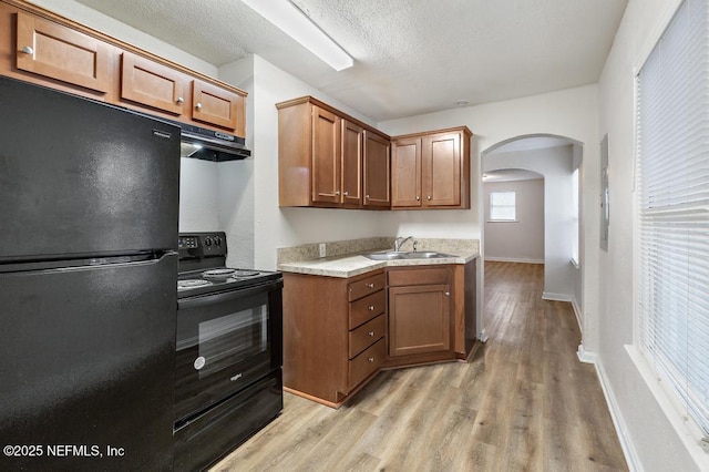 kitchen featuring black appliances, a textured ceiling, sink, and light hardwood / wood-style flooring