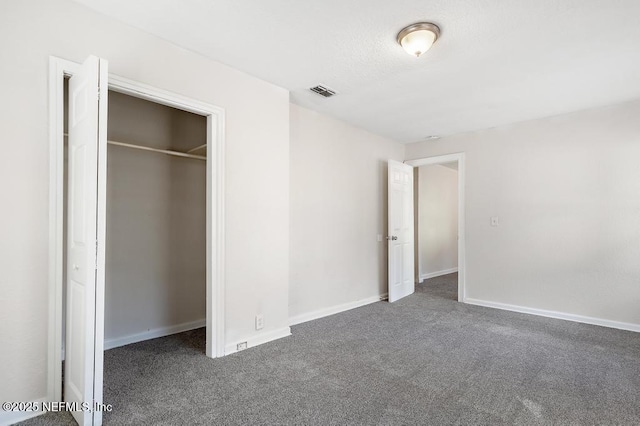 unfurnished bedroom with dark colored carpet and a closet