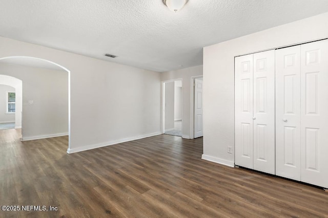 unfurnished bedroom featuring dark hardwood / wood-style flooring, a closet, and a textured ceiling