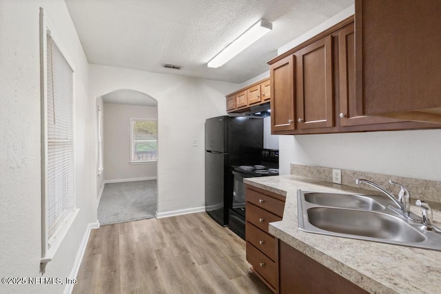 kitchen with sink, light hardwood / wood-style flooring, a textured ceiling, and black range with electric cooktop