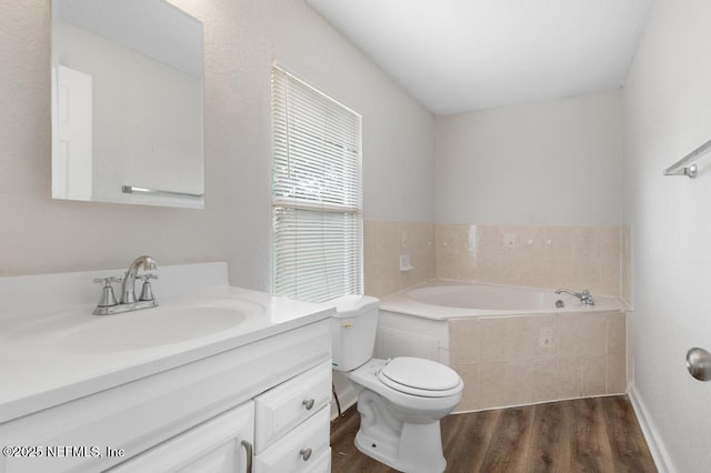 bathroom featuring tiled bath, hardwood / wood-style floors, vanity, and toilet