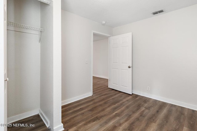 unfurnished bedroom featuring a closet and dark wood-type flooring