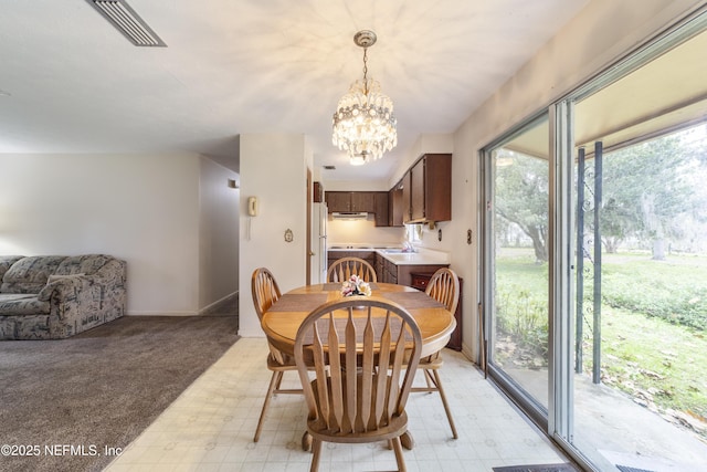 dining space featuring light carpet, a notable chandelier, and sink