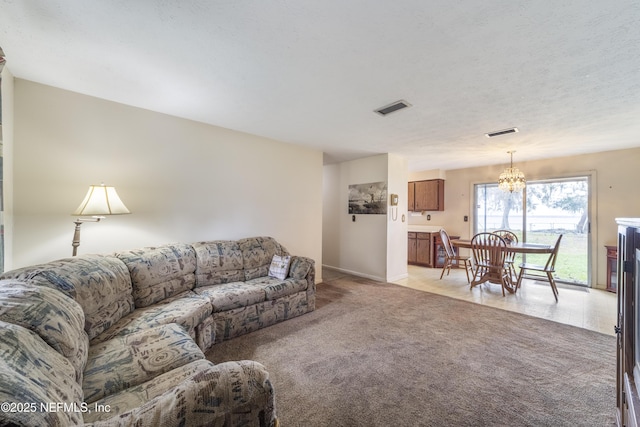 living room with a textured ceiling, light colored carpet, and an inviting chandelier