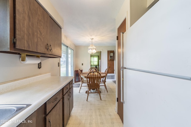 kitchen featuring sink, an inviting chandelier, pendant lighting, and white refrigerator