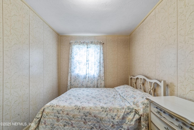 bedroom featuring a textured ceiling, crown molding, and wooden walls