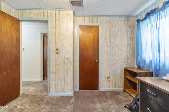 carpeted office space with a textured ceiling and wooden walls