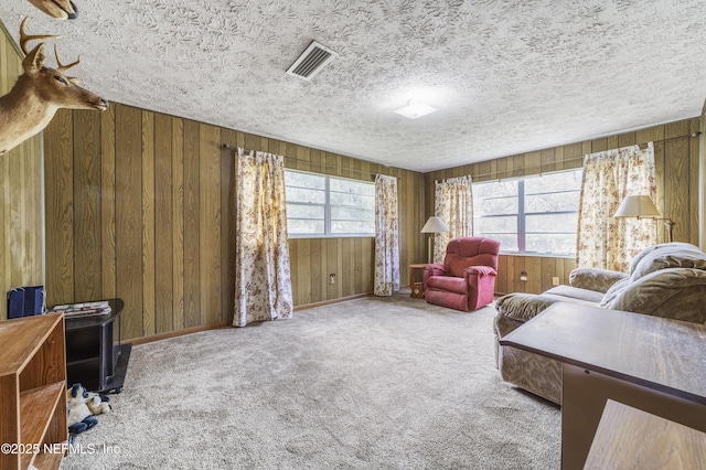 carpeted living room with wood walls and a textured ceiling