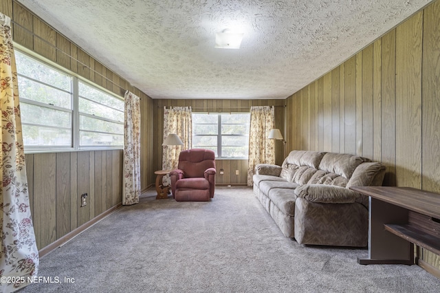 carpeted living room featuring a healthy amount of sunlight, a textured ceiling, and wooden walls