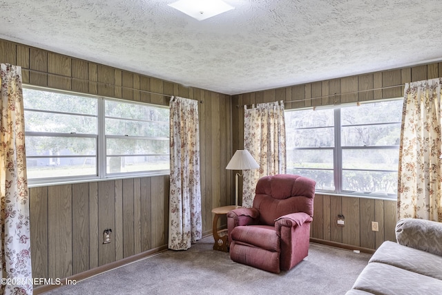 living area featuring wooden walls, plenty of natural light, and light carpet