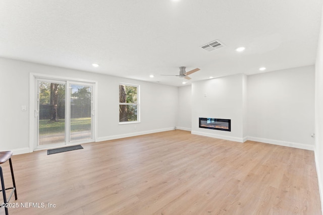 unfurnished living room featuring ceiling fan, a healthy amount of sunlight, and light hardwood / wood-style floors