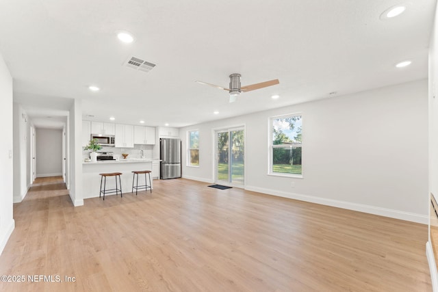 unfurnished living room featuring ceiling fan and light wood-type flooring