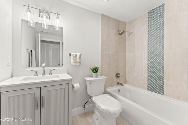 full bathroom featuring vanity, tiled shower / bath combo, a textured ceiling, and toilet