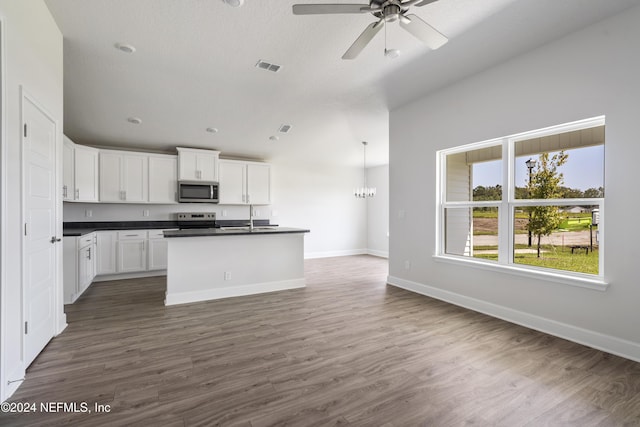 kitchen featuring appliances with stainless steel finishes, white cabinetry, lofted ceiling, sink, and an island with sink