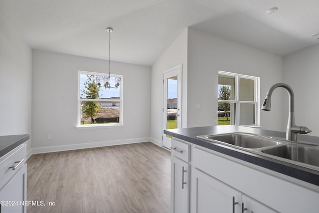 kitchen featuring sink, light hardwood / wood-style flooring, hanging light fixtures, white cabinets, and a chandelier