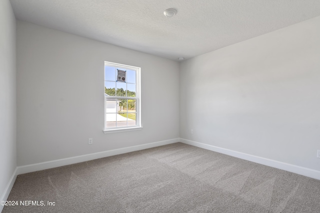 unfurnished room featuring carpet and a textured ceiling