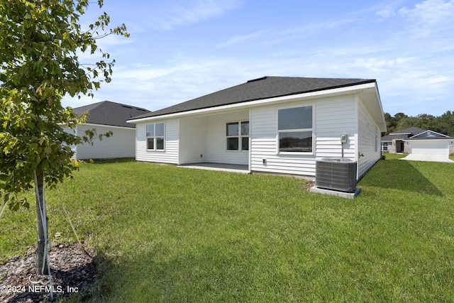 rear view of house with central AC, a patio area, and a lawn