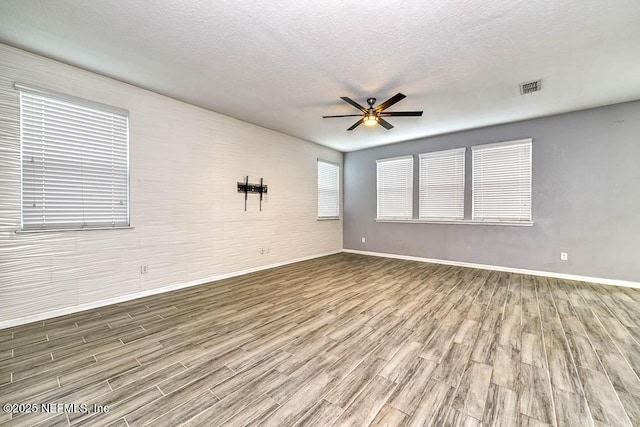 spare room featuring ceiling fan, wood-type flooring, and a textured ceiling