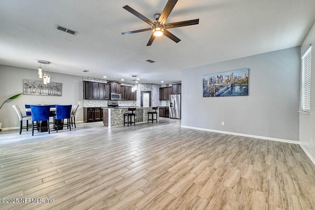 unfurnished living room with ceiling fan, light wood-type flooring, and a textured ceiling