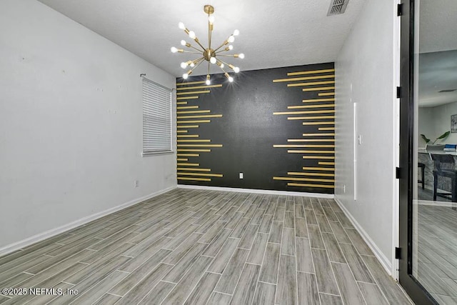 empty room with a stone fireplace, a textured ceiling, and a notable chandelier