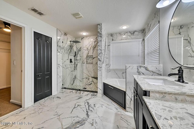 bathroom featuring vanity, shower with separate bathtub, and a textured ceiling