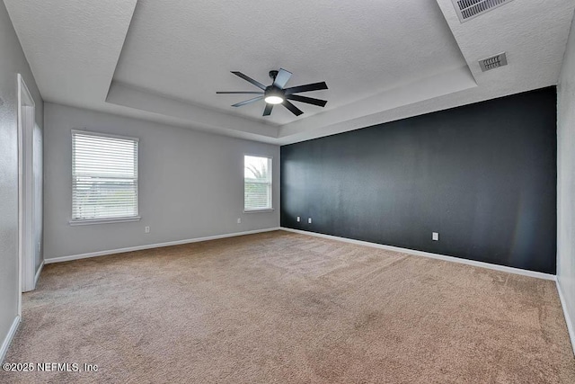 carpeted spare room with a textured ceiling, a raised ceiling, and ceiling fan