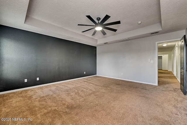 carpeted spare room with a tray ceiling, ceiling fan, and a textured ceiling