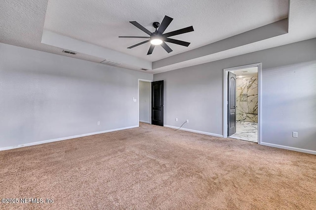 empty room with carpet flooring, ceiling fan, and a raised ceiling