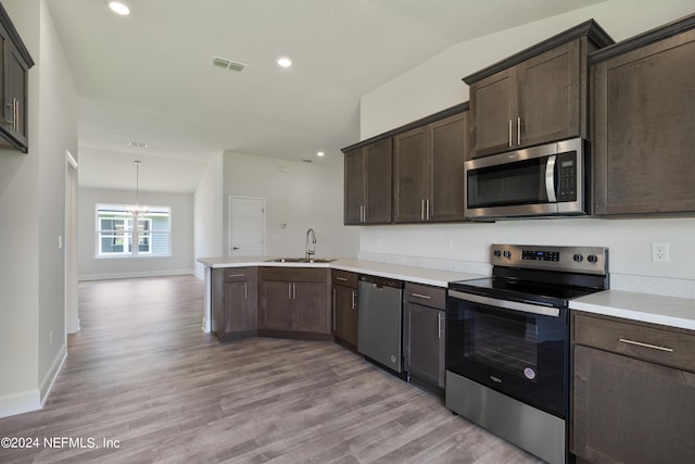 kitchen featuring sink, stainless steel appliances, dark brown cabinetry, kitchen peninsula, and light wood-type flooring