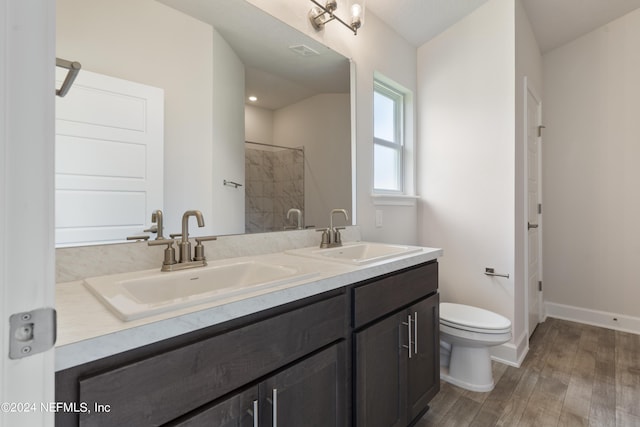 bathroom with wood-type flooring, vaulted ceiling, vanity, and toilet