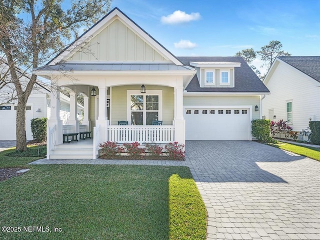 view of front of home featuring a porch, a garage, and a front lawn